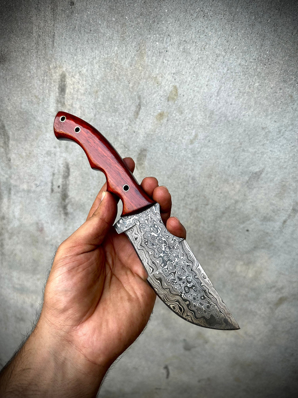 Custom Handmade Damascus Steel Tracker Knife with red Micarta Handle and leather sheath.